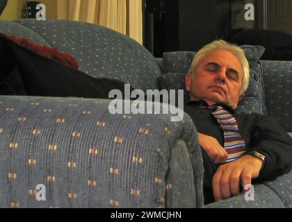 Uomo maturo che dorme su un divano in un soggiorno Foto Stock