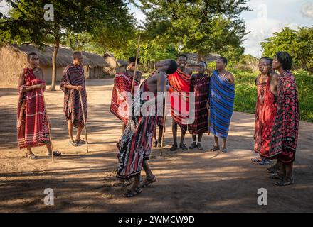 Un gruppo di guerrieri Maasai cantano ed eseguono la tradizionale danza del salto nel loro villaggio di Mikumi, Tanzania Foto Stock