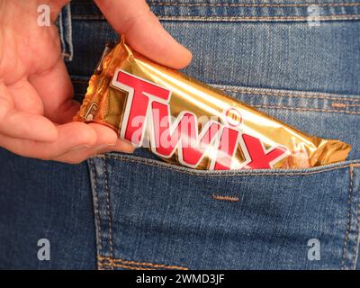 Tambov, Federazione Russa - 23 gennaio 2024 Una donna che porta a mano la barretta di cioccolato Twix in una tasca posteriore di jeans. Foto Stock