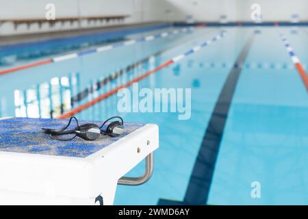 Gli occhiali da bagno riposano sul bordo di una piscina in una struttura interna Foto Stock