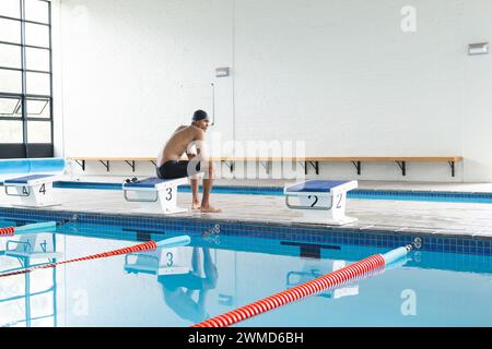 Il giovane nuotatore birazziale maschile si prepara a tuffarsi in una piscina coperta con spazio fotocopie Foto Stock