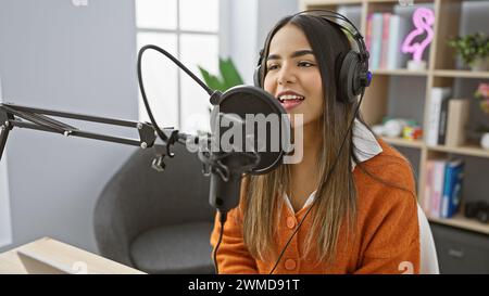 Una giovane donna ispanica si impegna come ospite in uno studio radiofonico, ritraendo un'aria di professionalità e fascino. Foto Stock