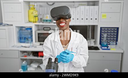 Scienziata afroamericana che conduce ricerche mediche in laboratorio, utilizzando occhiali di realtà virtuale all'avanguardia per una videochiamata dinamica Foto Stock