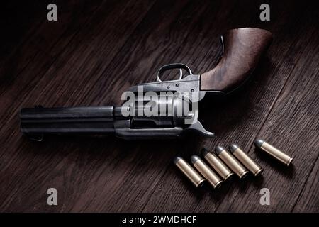 Revolver Peacemaker calibro 45 vecchio ovest con cartucce su tavolo in legno Foto Stock