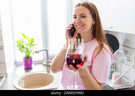 Donna sorridente che parla al telefono con Wine Foto Stock