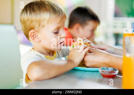 Ragazzo che mangia pizza con famiglia a tavola Foto Stock