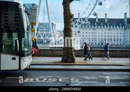 11 febbraio 2024 - Londonuk : persone che camminano a londra vicino all'occhio di londra con la parte anteriore del pullman visibile Foto Stock