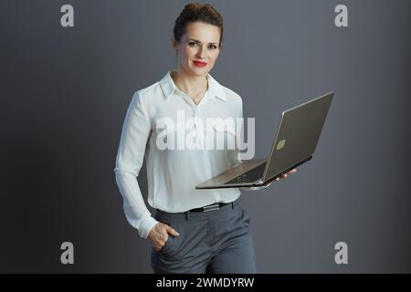 elegante donna d'affari in camicetta bianca con laptop isolato in grigio. Foto Stock