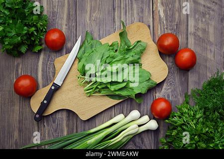 Verdure fresche. Dieta. Mangiare sano pomodori, ravanelli, cipolle verdi, spinaci, prezzemolo, aneto, coriandolo, aglio su fondo di legno. Eati sani Foto Stock