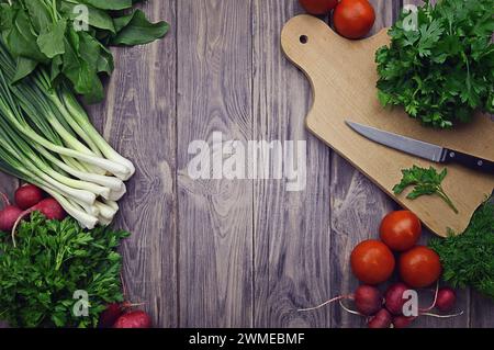 Verdure fresche. Dieta. Mangiare sano pomodori, ravanelli, cipolle verdi, spinaci, prezzemolo, aneto, coriandolo, aglio su fondo di legno. Eati sani Foto Stock