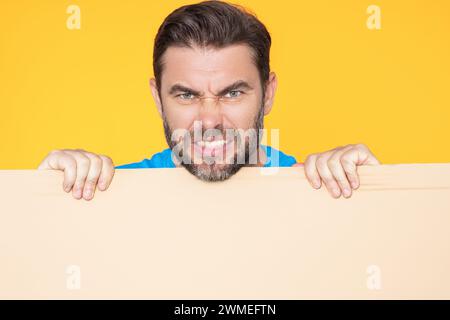 L'uomo arrabbiato ha un cartello bianco. Cartellino pronto per il prodotto. Uomo che mostra un cartello vuoto sullo sfondo isolato dello studio. Lavagna vuota vuota Foto Stock