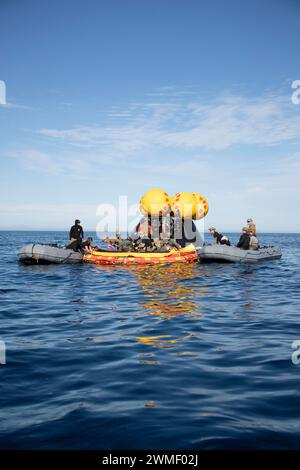 I marinai della Marina degli Stati Uniti assegnati all'Explosive Ordnance Disposal Mobile Unit 1 provano il recupero delle zattere di salvataggio mentre sono in corso con la USS San Diego (LPD 22) per il Recovery test 11 della NASA, 23 febbraio 2024. In preparazione della missione Artemis II della NASA, che invierà quattro astronauti a Orion oltre la Luna, la NASA e il Dipartimento della difesa condurranno una serie di test per dimostrare e valutare i processi, le procedure e l'hardware utilizzati nelle operazioni di recupero per le missioni lunari con equipaggio. La Marina degli Stati Uniti ha molte capacità uniche che la rendono un partner ideale per sostenere la NASA, compreso ITS Foto Stock