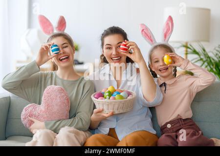 Buona vacanza. Madre e le sue figlie con uova da pittura. La famiglia festeggia la Pasqua. Le ragazze cute dei bambini stanno portando le orecchie conigliate. Foto Stock