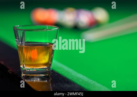 Due bicchieri di whiskey sul tavolo da biliardo e palline da biliardo sullo sfondo Foto Stock
