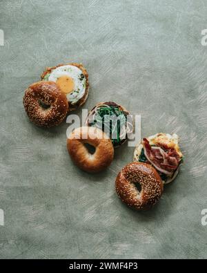 Un angolo alto di tre panini da colazione su un piatto con bagel, uova, formaggio e avocado Foto Stock