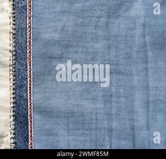 Sfondo in denim blu e grigio chiaro con cucitura rossa. Tessuto jeans di colore azzurro con bordo decorativo. Copia spazio per il testo Foto Stock