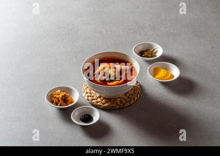 Piatto coreano di maiale agrodolce riso con spaghetti di vetro saltati e verdure pesce e verdure fritti in padella zuppa piccante di spaghetti di pesce Foto Stock