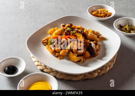 Piatto coreano di maiale agrodolce riso con spaghetti di vetro saltati e verdure pesce e verdure fritti in padella zuppa piccante di spaghetti di pesce Foto Stock