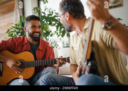Migliori amici, musicisti che si stanno ammazzando insieme. Suonare musica alla chitarra insieme, divertirsi. Concetto di amicizia maschile, bromance. Foto Stock