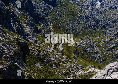 La strada a serpentina si snoda attraverso un paesaggio roccioso di montagna in una giornata di sole, Maiorca Foto Stock