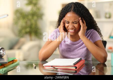 Lo studente nero stressato soffre di mal di testa mentre studiava a casa Foto Stock