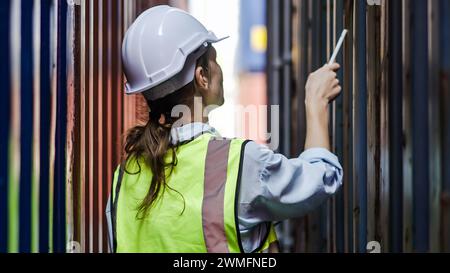 Una lavoratrice portuale che controlla i container Foto Stock