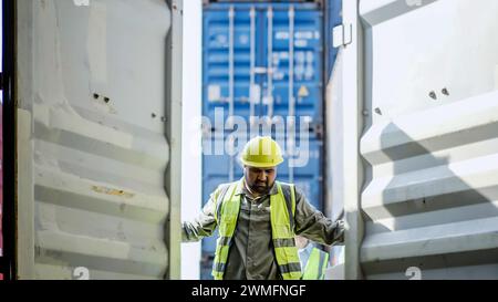 Un uomo che apre un container merci in un terminal logistico Foto Stock