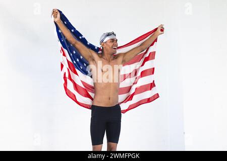 Il giovane nuotatore birazziale maschile celebra con una bandiera americana, con spazio copia Foto Stock