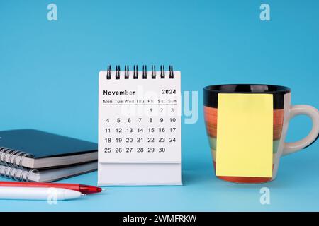 Calendario da scrivania di novembre 2024 con nota adesiva sulla tazza di caffè Foto Stock