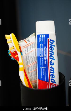 Spazzolini da denti e tubo per dentifricio accanto alla tazza Foto Stock