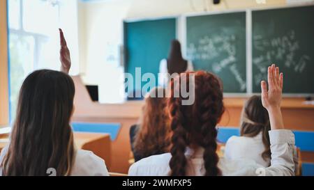 Le studentesse alzano le mani in classe di matematica. Foto Stock