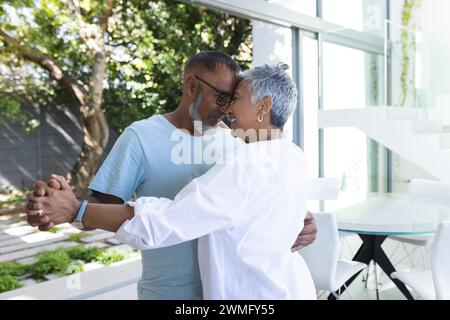 La coppia birazziale senior condivide un momento tenero a casa Foto Stock