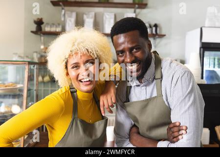 Una coppia allegra e variegata che lavora insieme in un accogliente caffè Foto Stock