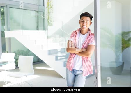 Il giovane uomo asiatico si trova in un luminoso spazio ufficio con spazio di copia Foto Stock