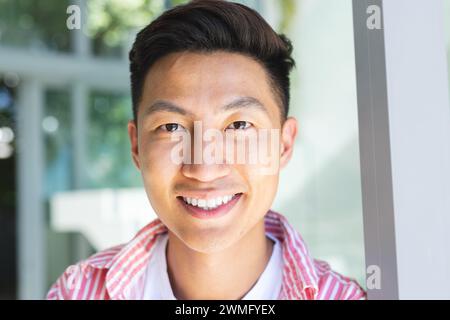 Un giovane asiatico sorride brillantemente Foto Stock