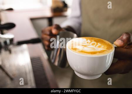 Un barista afroamericano presenta un cappuccino appena fatto con spazio per le copie Foto Stock