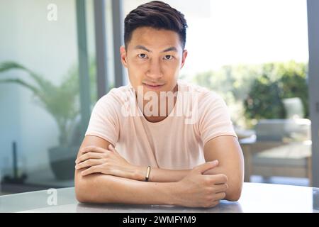 Il giovane asiatico siede con fiducia a un tavolo Foto Stock