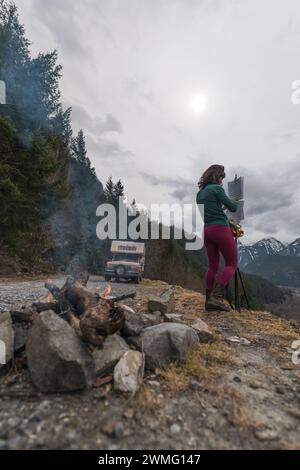 Donna che suona il sassofono accanto a un camper in montagna Foto Stock