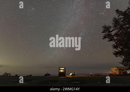 camper parcheggiato davanti all'oceano sotto le stelle Foto Stock