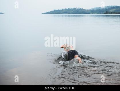 Un uomo con tatuaggi si tuffa nel lago Kivu, Ruanda Foto Stock