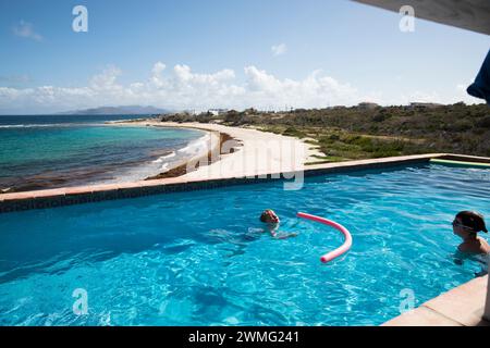 I fratelli nuotano nella piscina Infinity accanto alla spiaggia dei Caraibi Foto Stock