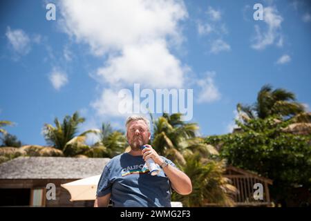 L'uomo Millennial dai capelli grigi spruzza la crema solare sul viso Foto Stock