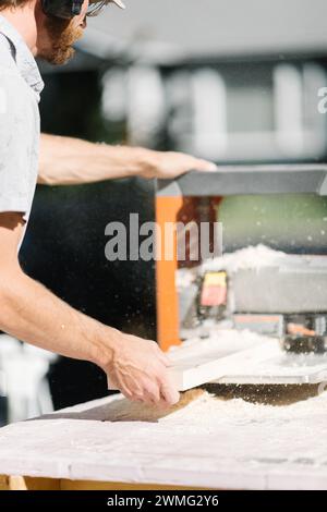 Falegname sagomando con precisione il legno con la pialla. Foto Stock