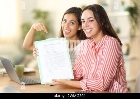 I telelavoratori felici che mostrano un contratto firmato o un modulo compilato a casa Foto Stock