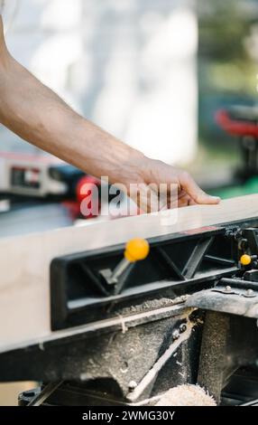 Falegname taglia con precisione il legno con una sega ad angolo. Foto Stock