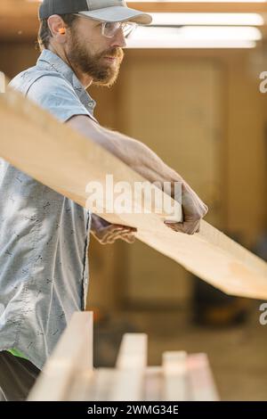 Falegname che ispeziona il legno al banco di lavoro Foto Stock