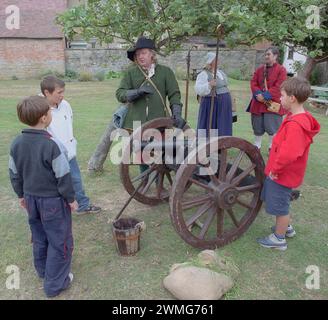 Foraggio per cannoni? I giovani del XXI secolo incontrano il combattente in costume della Sealed Knot Society del XVII secolo con cannoni al Fleece Inn del National Trust, Bretforton, Worcestershire, durante una dimostrazione esterna della rievocazione della guerra civile inglese. Foto Stock