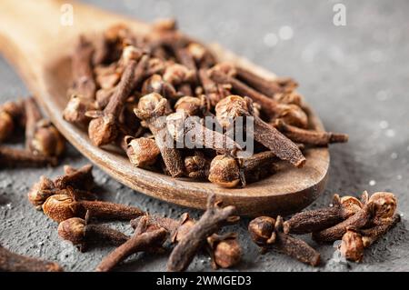 Chiodi di garofano secchi in un recipiente di legno su un tavolo rustico, spezie fresche alle erbe Foto Stock