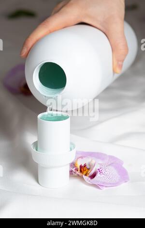 Il processo di versamento di detergente liquido eco-gel naturale dal biberon al tappo Foto Stock