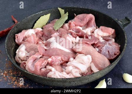 Vista dall'alto di una padella su cui giace carne di maiale tagliata a pezzi, pronta per la cottura. Foto Stock